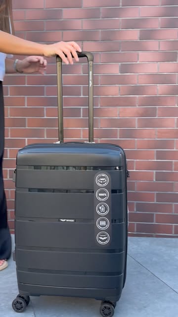Чорна валіза Flybag біля цегляної стіни